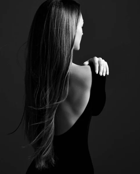 Jovem mulher bonita modelo de pé para trás no vestido com costas abertas e mostrando seu lindo cabelo liso longo e sedoso — Fotografia de Stock