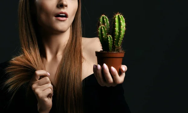 Απογοητευμένη γυναίκα με μακριά μεταξένια ίσια μαλλιά σε μαύρο σώμα κρατώντας το φυτό κάκτος σε γλάστρα και σε σύγκριση με τα σχισμένα άκρα — Φωτογραφία Αρχείου