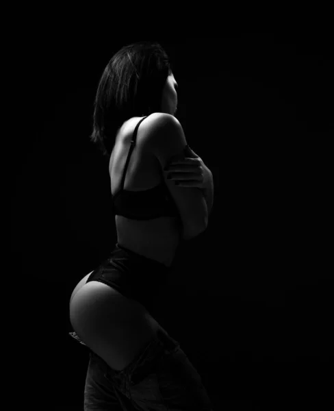 Σιλουέτα της νεαρής πολύ σέξι μελαχρινή γυναίκα μοντέλο σε μαύρο εσώρουχο στέκεται και αγκαλιάζει τον εαυτό της δείχνει τέλεια γλουτούς — Φωτογραφία Αρχείου