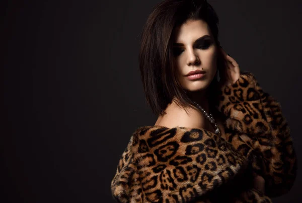 Portrét mladé hezké sexy brunetky žena modelka v leopard kožich kabát s nahými rameny v perleťovém náhrdelníku při pohledu dolů — Stock fotografie