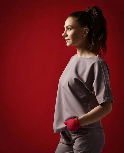 Young pretty brunette woman doctor gynecologist in red latex gloves and medical uniform stands looking at copy space — Stock Photo, Image