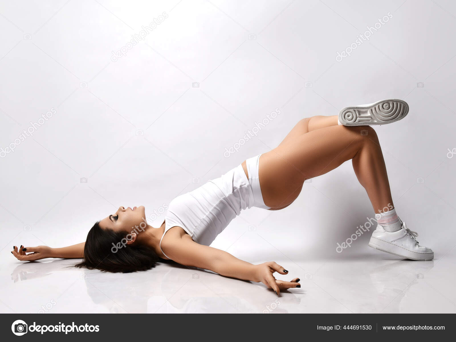 Young sexy brunette fitness woman in white underwear and sneakers is lying  on floor lifting her pelvic body up Stock Photo by ©dml5050 444691530