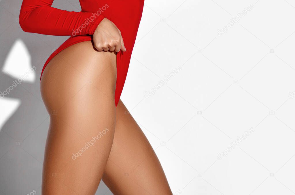 Perfect slim toned young body of the girl legs and hip wear red body swimsuit . An example of sports , fitness or plastic surgery
