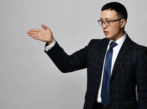 Portrait of asian businessman expert analyst in official suit, tie and glasses showing direction with his hand