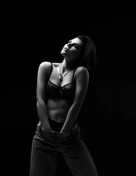 Ενθουσιασμένη σέξι γυναίκα με μαύρα εσώρουχα στέκεται κρατώντας τα χέρια κάτω στο παντελόνι αγγίζοντας τον εαυτό της με το κεφάλι της επάνω — Φωτογραφία Αρχείου