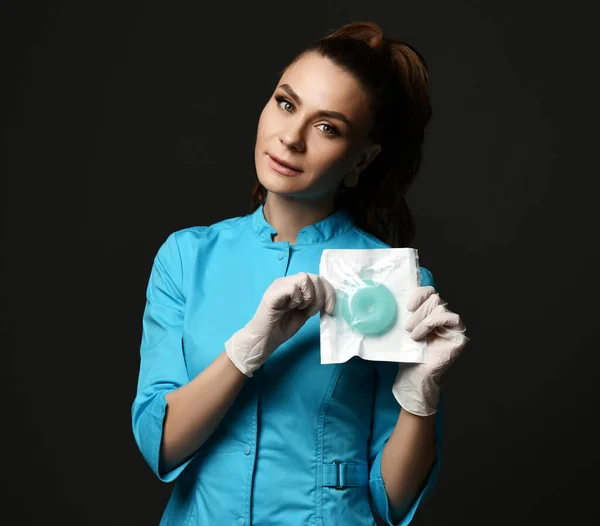 Jeune femme médecin infirmière en uniforme bleu et gants de protection en latex démontre des outils médicaux spéciaux qu'elle détient — Photo