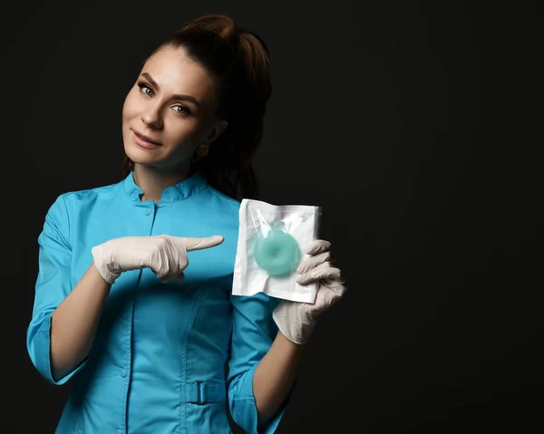 Young woman doctor nurse in blue uniform and protective latex gloves shows points finger at special medical tools — Stock Photo, Image