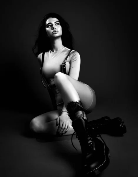 性感纤细漂亮的黑发女人，身穿丝质西服，脚镣和靴子坐在地板上向上看 — 图库照片