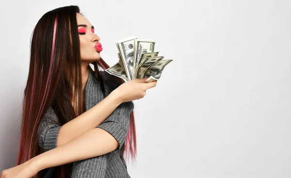 Mooie brunette zakenvrouw in kantoor casual pak ziet er gelukkig winnaar glimlach en houden bundels dollars cash notes geld — Stockfoto