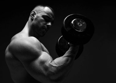 Kaslı erkeklerin portresi, vücut geliştirici, dambıl kaldırma, ona bakarak pazılar için egzersiz yapma.