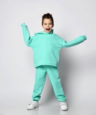 Modern yeşilli, nane rengi kapüşonlu, pantolonlu ve beyaz spor ayakkabılı çocuk kollarının arasında el ele duruyor.