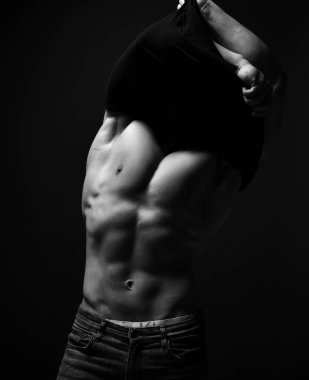 Kotlu ve iç çamaşırlı vahşi bir sporcunun güçlü vücudunu şişirmiş. Elbiselerini çıkartıyor.