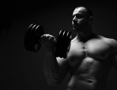 Kaba, güçlü erkek atlet. Kaba etleriyle egzersiz yapıyor. Seksi vücudunu ve pazılarını gösteriyor.