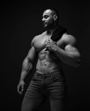 Gülümseyen kaslı adam, sporcu omzunda yarı çıplak duruyor, fotokopi alanına bakıyor.