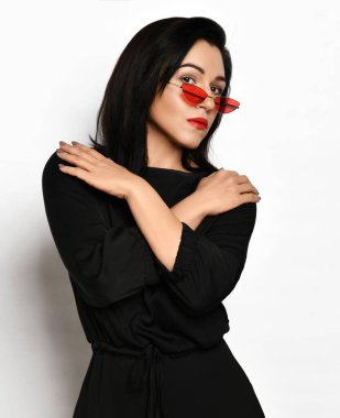 Şık, siyah elbiseli, güvenilmez, esmer kadın kollarını kavuşturup insanları kendinden uzaklaştırıyor.