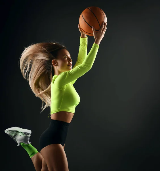 Basketball woman player spinning ball on finger on concrete loft wall background