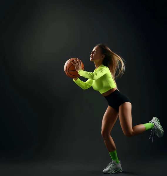 Joven mujer rubia deportiva con el pecho grande en ropa deportiva apretada, top, pantalones cortos, calcetines altos y zapatillas de deporte juega baloncesto — Foto de Stock