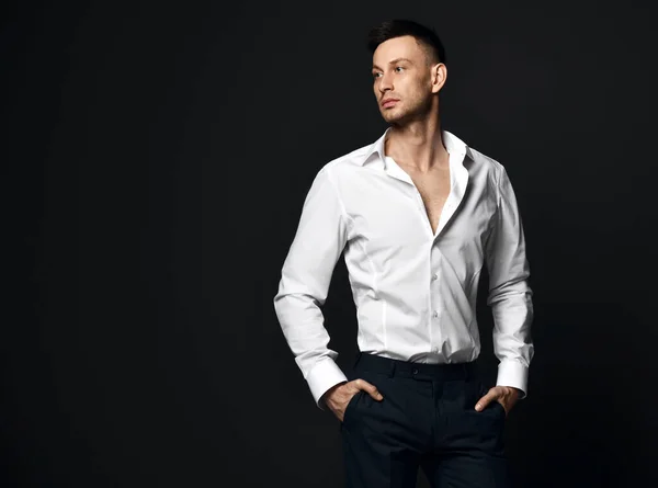 Portrait of young self-confident businessman in official suit trousers and shirt stands looking aside at copy space — Stock Photo, Image