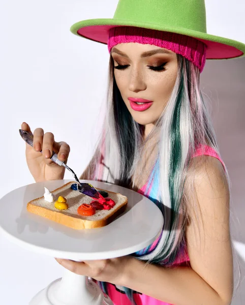 身穿粉色衬衫，头戴绿色帽子，涂满油彩油彩的年轻女性现代艺术家的画像 — 图库照片