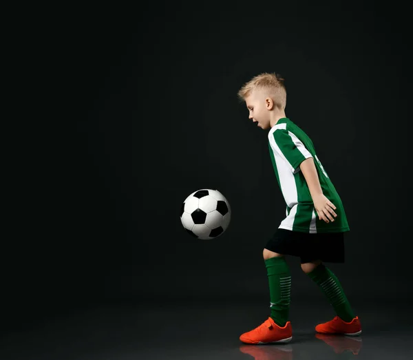 Estudante esportivo ativo em uniforme de jogador de futebol joga com bola, vai chutar e marcar um gol — Fotografia de Stock