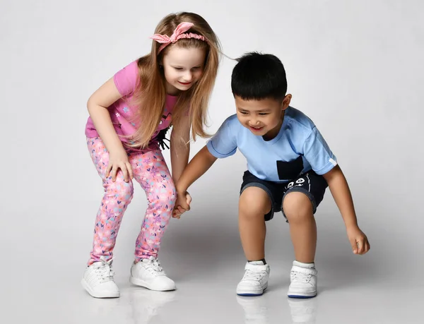 Dos divertidos niños amigos juguetones niño y niña en ropa de verano se paran juntos mirando hacia abajo, notó algo en el suelo — Foto de Stock