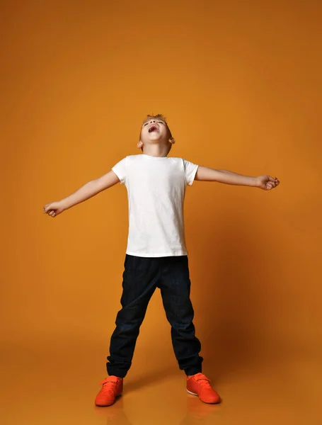 Talentovaný kluk, teenager, školák v modrých džínách a bílých prázdných tričkách, ruce natažené a zpívající — Stock fotografie