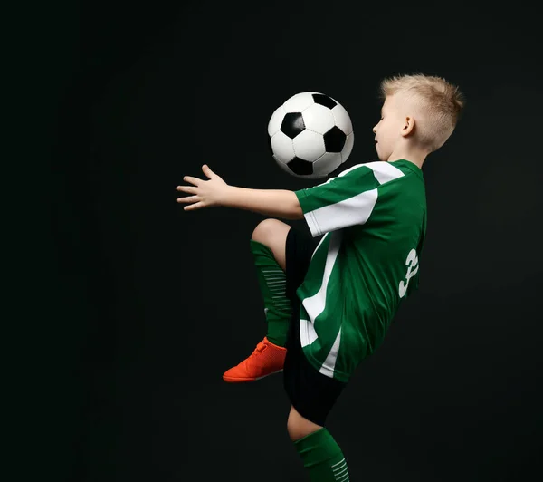 Портрет юного футболіста, хлопчика в червоно-білій смугастій формі вдарив по м'ячу коліном, контролюючи — стокове фото