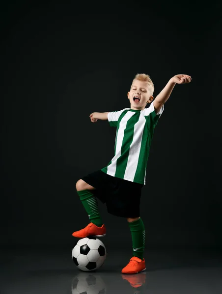 Estudante da escola de futebol, menino de uniforme branco vermelho fica com bola sob o pé e mantém os braços estendidos — Fotografia de Stock