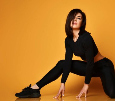 Siyah spor kıyafetli genç, seksi bayan bacaklarını açıyor ve kameraya bakıyor.