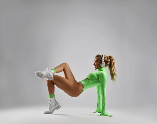 Sexy blonde woman, sporty girl in stylish sportswear jumpsuit and white brutal shoes does pelvic lifts with legs crossed — Stock Photo, Image