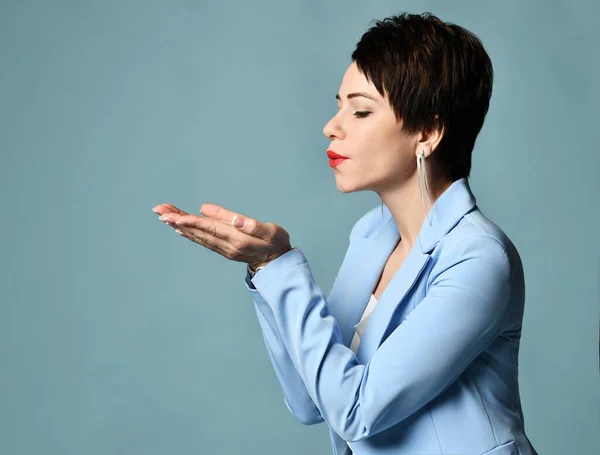 Sinnliche, aber kraftvolle brünette Geschäftsfrau, erfahrene Managerin im blauen Business-Anzug, die etwas von ihren Handflächen bläst — Stockfoto