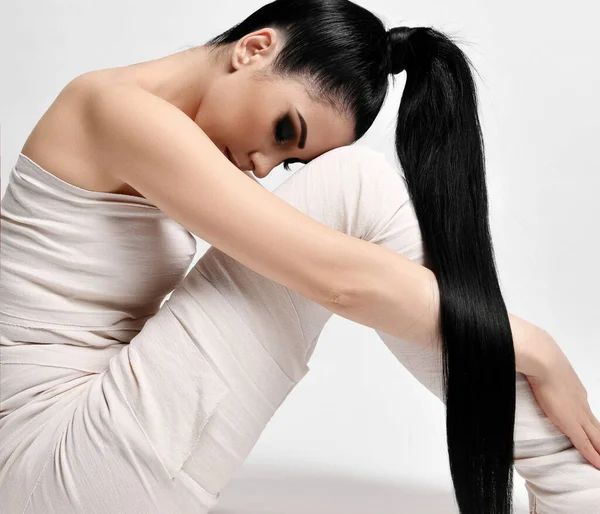 Side view of young brunette woman with ponytail hairstyle sitting in medical bandages on body, body wrap, looking down — Fotografia de Stock