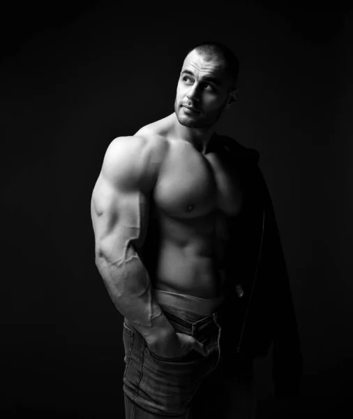 Όμορφος βίαιος άντρας με γυμνό πάνω μέρος με τζιν και εσώρουχα που δείχνει μυς δικέφαλους και κοιτάει στην άκρη. — Φωτογραφία Αρχείου