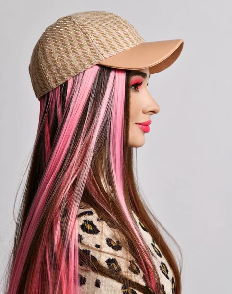 Retrato de perfil de mujer hermosa sonriente con hebras de color rosa y maquillaje brillante en gorra beige y chaqueta de leopardo — Foto de Stock