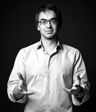 Tıraşsız, orta yaşlı bir adamın siyah beyaz portresi. El ele tutuşmuş, avuçlar havada.