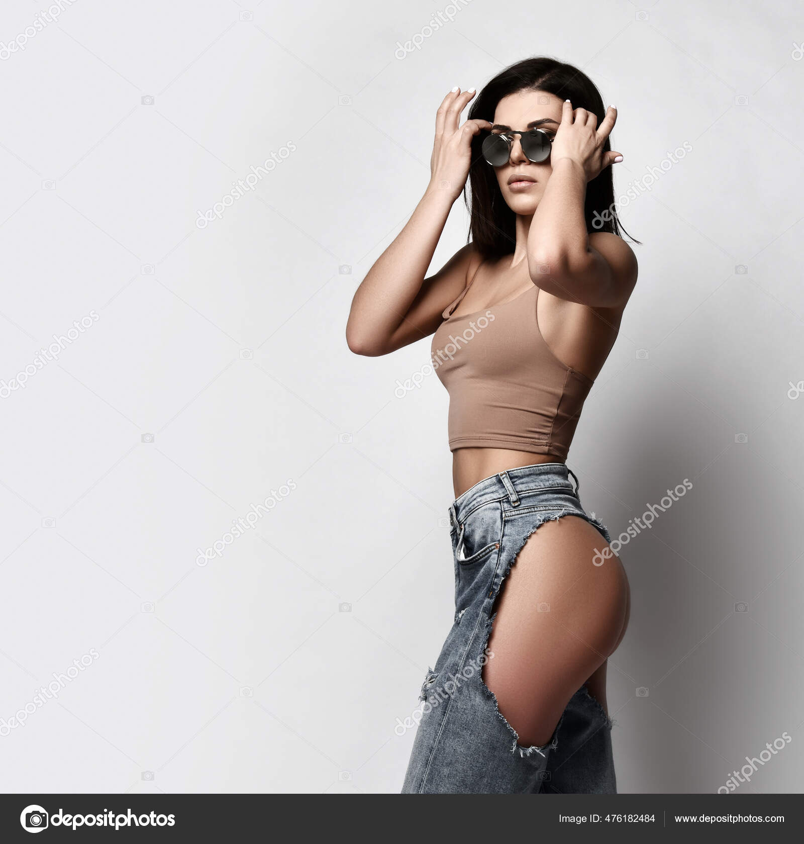 Self-confident sexy adult woman is walking in torn jeans with naked butt, ass, sunglasses and photo