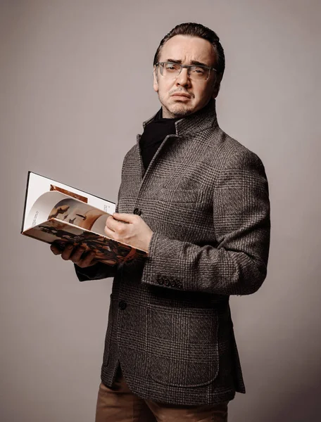 Retrato de homem intelectual esnobe crítico literário em jaqueta quadriculada e cachecol preto olhando através de novo livro — Fotografia de Stock