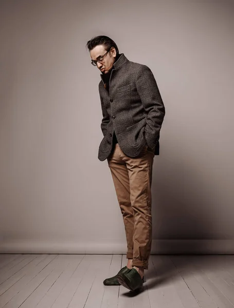 Портрет снобистского интеллигентного взрослого мужчины в клетчатой куртке и черном шарфе, смотрящего на подошву обуви — стоковое фото