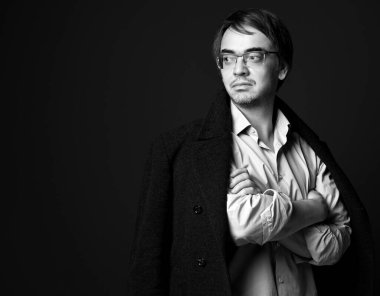 Siyah ve beyaz. Güçlü, kendine güvenen, beyaz gömlekli ve kolları bağlı, omuzlarında tişörtlü yetişkin bir adam.