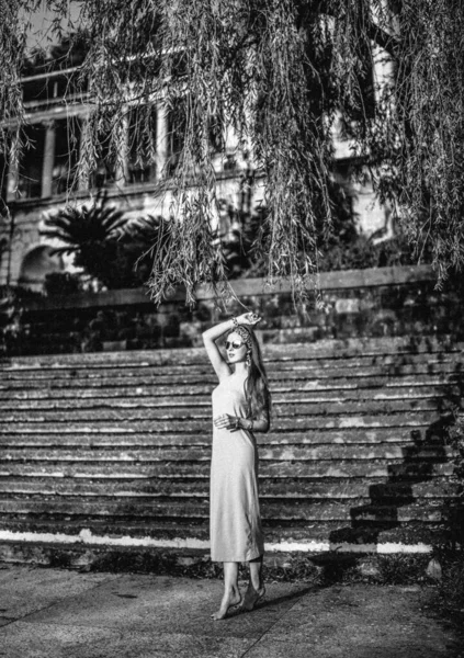 Schwarz-weißes, ausgewachsenes Porträt einer jungen, schlanken Touristin auf der Treppe des alten Schlosses, des Palastes — Stockfoto