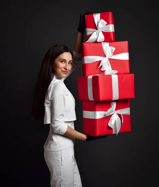 Attraente giovane donna positiva medico dentista in uniforme bianca e guanti in lattice in piedi e in possesso di mucchio di scatole regalo vacanza — Foto Stock