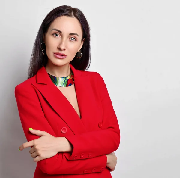 Retrato de mulher de negócios com maquiagem permanente em jaqueta vermelha e jóias modernas de pé com os braços cruzados no peito — Fotografia de Stock