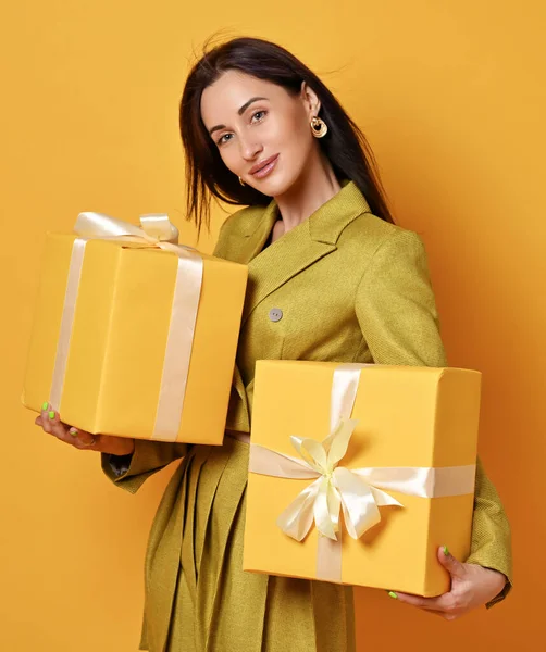Giovane donna bruna sorridente in gonna gialla e giacche corte, porta due scatole regalo gialle, regali — Foto Stock