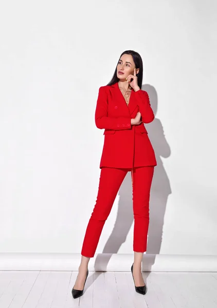 Jovem mulher de negócios morena inteligente em pantsuit oficial vermelho e sapatos de salto alto está segurando a mão na cabeça — Fotografia de Stock