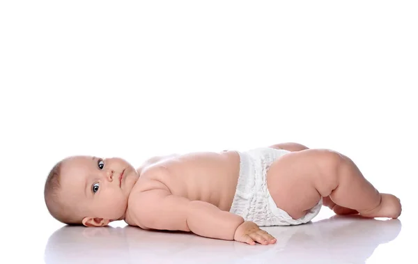 Bambino neonato bambina bambino in pannolino è sdraiato sulla schiena lateralmente alla fotocamera e guardando la fotocamera isolata su bianco — Foto Stock