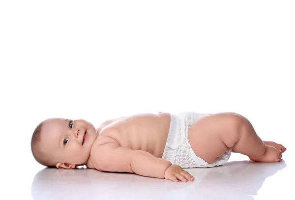 Happy smiling infant child baby girl kid in diaper is lying on her back sideways to camera and looking at camera — Stock Photo, Image