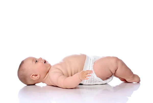 Spädbarn baby flicka unge i blöja ligger på ryggen i sidled till kameran glad leende tittar upp isolerad på vit — Stockfoto
