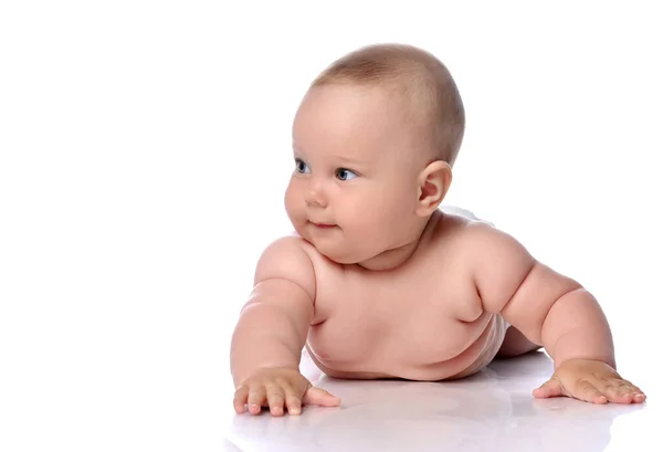 Sly, nyfiken spädbarn barn flicka unge i blöja ligger på magen, magen och tittar åt sidan — Stockfoto