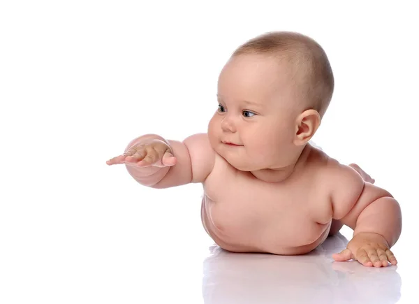 Niño bebé niña niño en pañal está acostado sobre su barriga, estómago, arrastrándose sosteniendo la mano hacia arriba y mirando a un lado —  Fotos de Stock