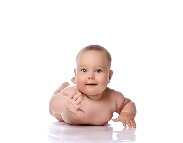 Happy curious infant child baby girl kid in diaper is lying on her tummy, stomach trying to reach, touch camera — Stock Photo, Image